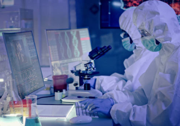Young multi-ethnic team during coronavirus lab tests. Working on computers. Map of disease outbreaks in background